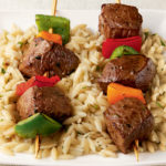 2 beef kabobs on bed or orzo pasta