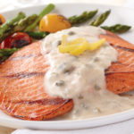 grilled salmon with lemon caper beurre blanc sauce served with asparagus and tomatoes
