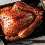whole basted golden brown turkey in roasting pan