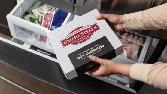 Woman removing a box of Omaha Steak from her freezer.