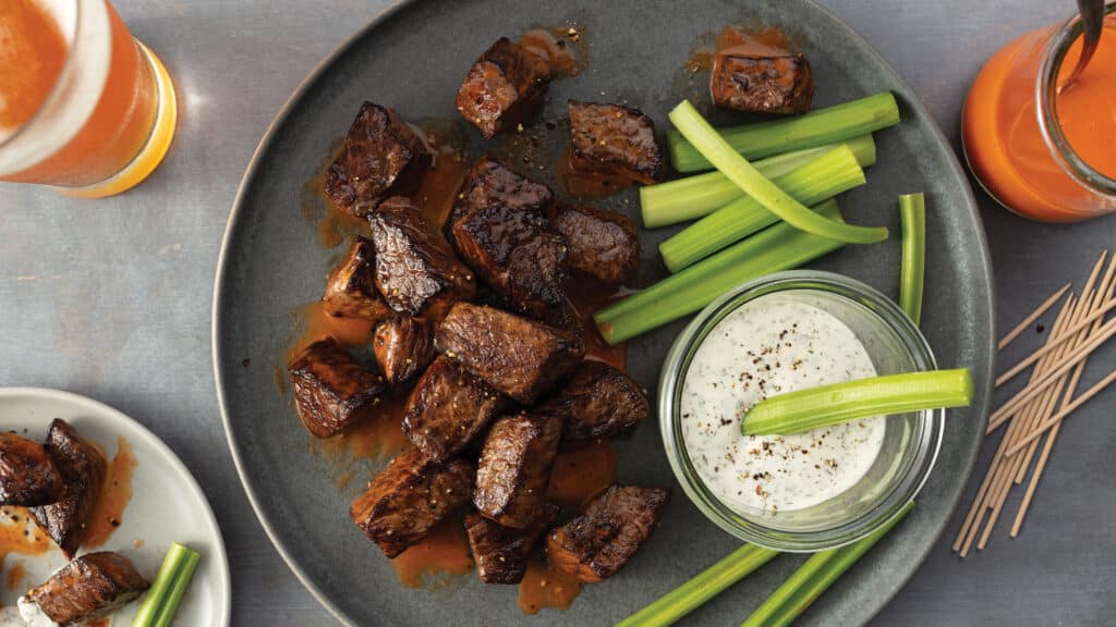 Buffalo sirloin tips on a plate with sliced celery and ranch
