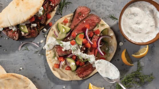 Gyros with medium-rare sliced top sirloin steak, fresh cucumbers, sliced red onions with drizzled tzatziki sauce