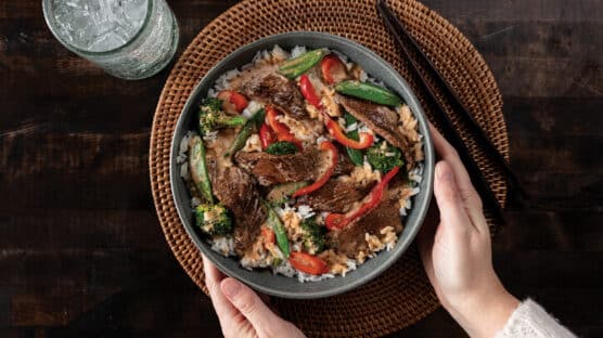 Grey bowl with thai curry beef on bed of rice with steamed vegetables