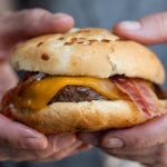 Person holding bourbon barbecue bacon cheeseburger
