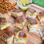 Ham and cheese sliders on a cutting board served with mustard sauce