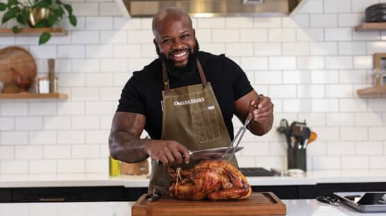 Chef Rose holding a serving fork knife over a whole cooked turkey