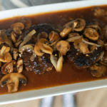 Salisbury steak patties covered in mushroom gravy on a white platter