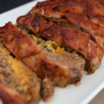 Meatloaf stuffed with cheese and pickles and topped with bacon
