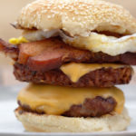 Breakfast burger with beef patty, American cheese, hashbrown, bacon and fried egg on a toasted bun