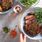 Grilled Ribeye with Arugula Salsa Verde and Grilled Fingerling Potatoes with romesco sauce served on a plate