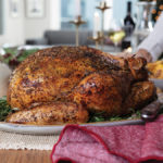 golden brown and crispy garlic-herb whole turkey served on a white platter on a holiday table