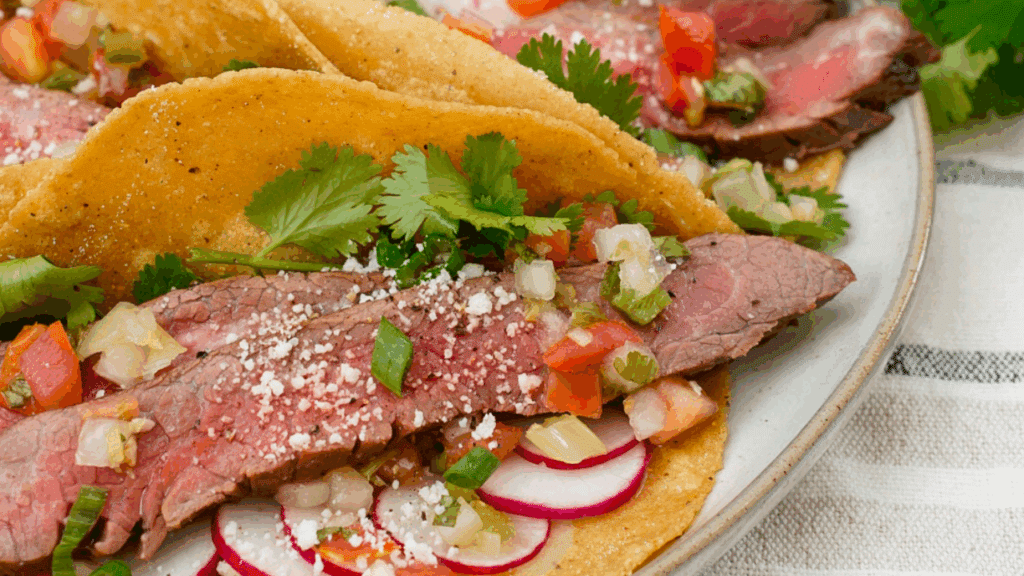 Tacos with sliced flank steak, sliced radishes, cilantro and salsa