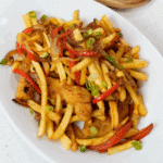 White plate with fries, sliced bell peppers and cripsy chicken tenders