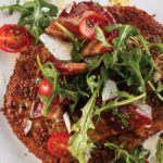 Pork Milanese served on a plate with arugula salad