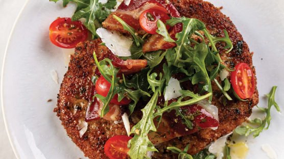 Pork Milanese served on a plate with arugula salad