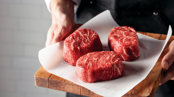 Person holiday cutting board with three well-marbled Butcher's Cut Ribeye steaks