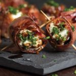 Dark grey tray with bacon-wrapped tenderloin tips stuffed with Maytag Blue Cheese