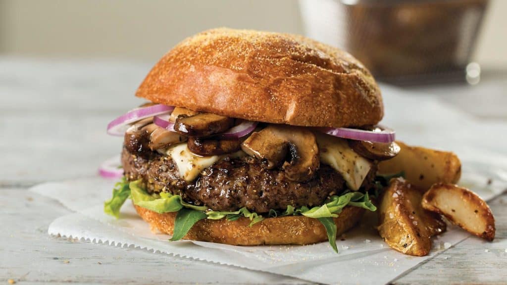 filet mignon burger with wild mushrooms, red onions, arugala and mayo on a brioche bun