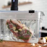 King Cut New York Strip steak in sealed bag with garlic and herbs in sous vide immersion circulator