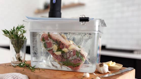King Cut New York Strip steak in sealed bag with garlic and herbs in sous vide immersion circulator