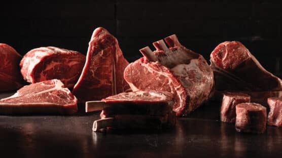 Group shot of raw beef cuts including T-bones, bone-in prime rib roast, filet mignon, boneless prime rib roast and cowboy ribeye