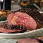 Holiday table setting with prime rib cooked medium-rare and sliced and served with horseradish sauce on the side