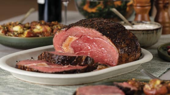 Holiday table setting with prime rib cooked medium-rare and sliced and served with horseradish sauce on the side