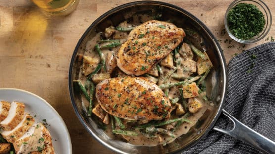 Chicken, green beans, and potatoes with sauce cooking in a skillet