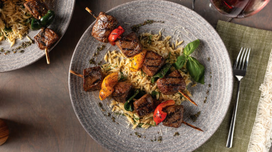 steak kabobs with parmesan orzo on plate