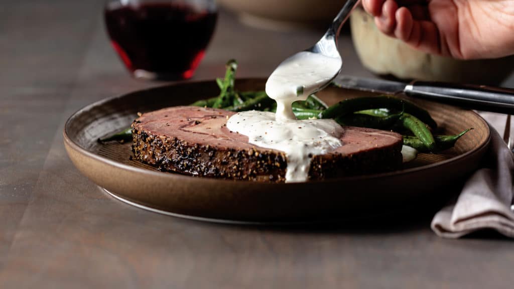 steak on plate covered in creamy horseradish sauce