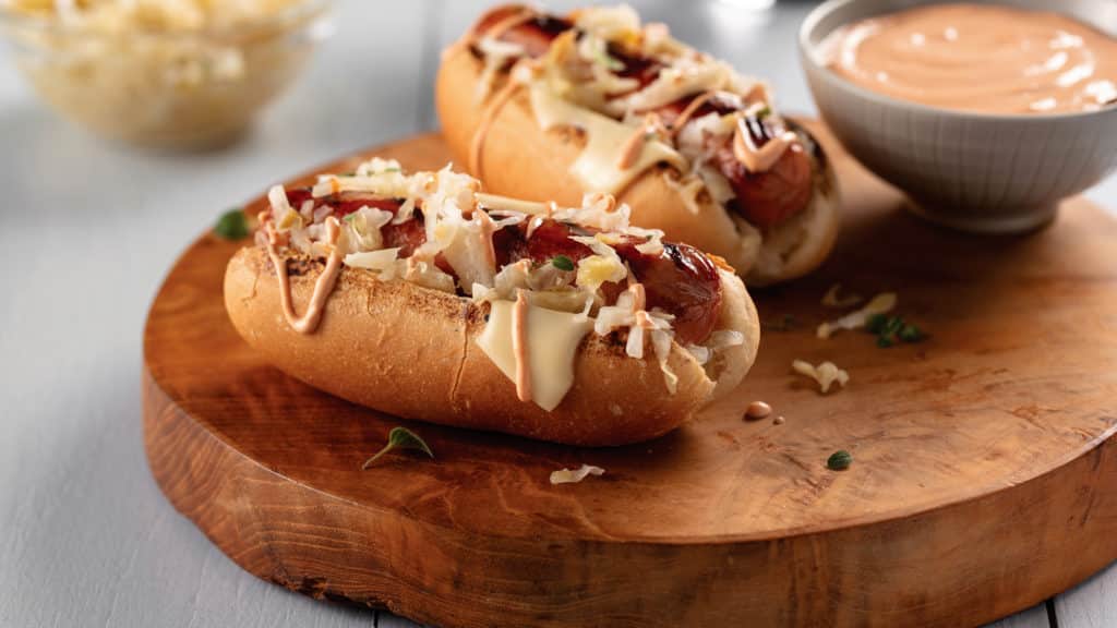 hot dog on bun covered in swiss cheese, sauerkraut and thousand island dressing