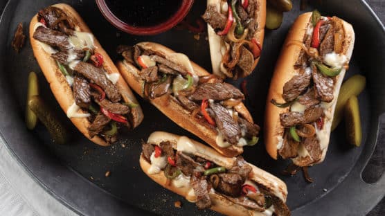 5 ribeye philly cheesesteaks with sauteed onions and peppers on toasted buns and served au jus