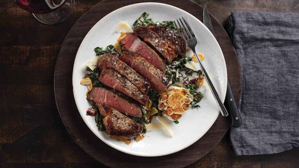 Garlic-Stuffed Ribeye Steaks with Creamy Garlic Chard on plate