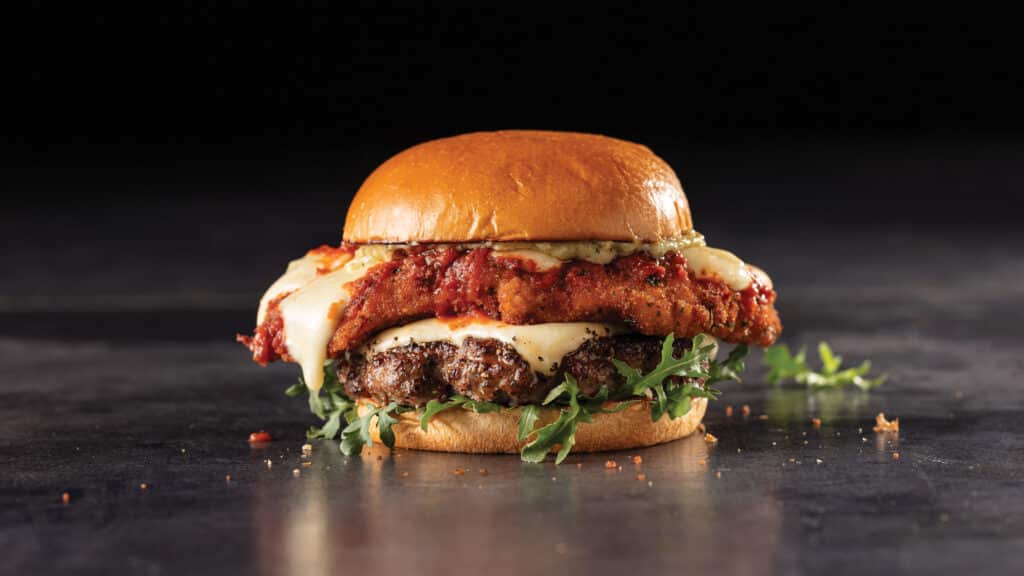Italian stallion burger with PureGround delmonico burgers, chicken parmesan, pesto mayo and arugula on a toasted brioche bun