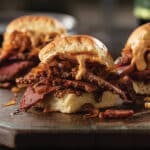 Three corned beef sliders with beer cheese sauce on a platter