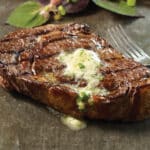 ribeye steak with garlic herb steak butter on it