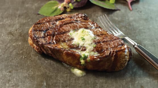 ribeye steak with garlic herb steak butter on it