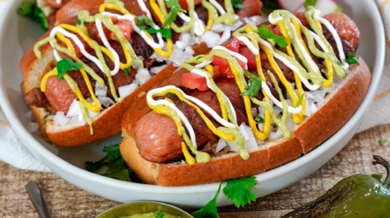 Two Sonoran hot dogs on white plate.