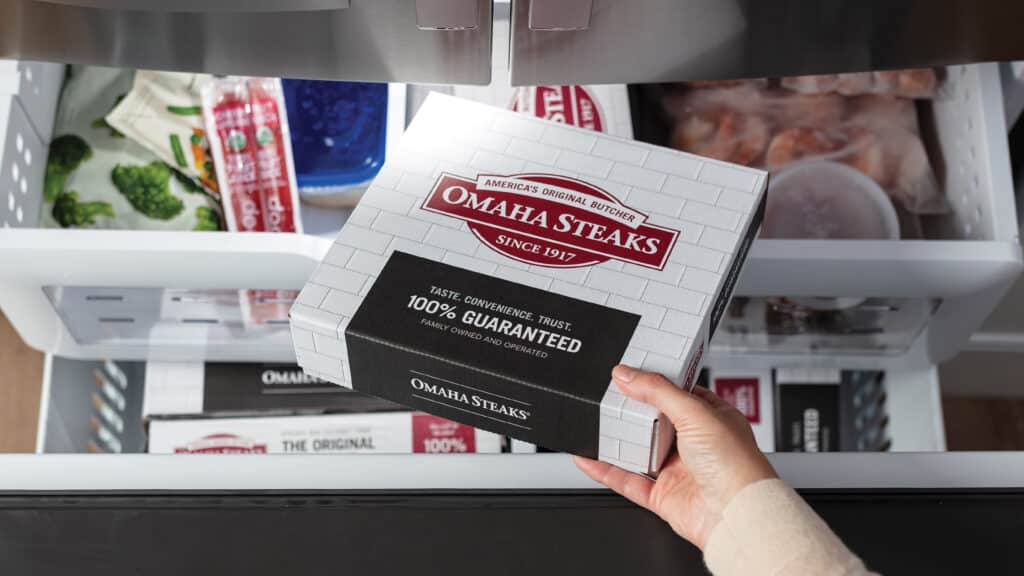 Box of Omaha Steaks being placed in a freezer.