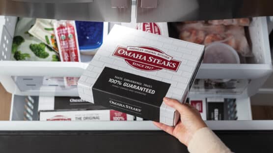 Box of Omaha Steaks being placed in a freezer.