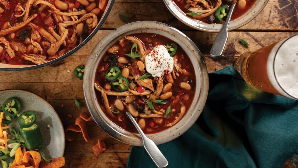 Table set with bowl of chicken and mushroom white bean chili.