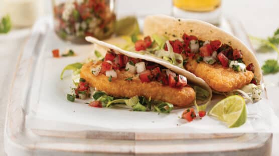 Two pub-style cod fish tacos with fresh pico de gallo on a tray.