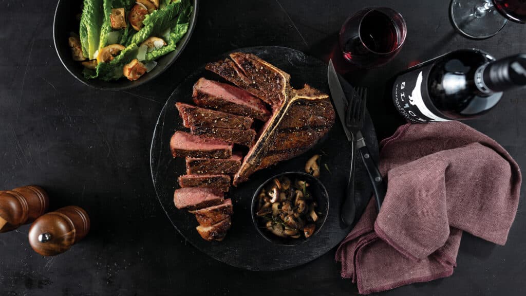 cooked t-bone steaks on black plate