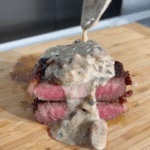 Chef spooning mushroom cream sauce over steak