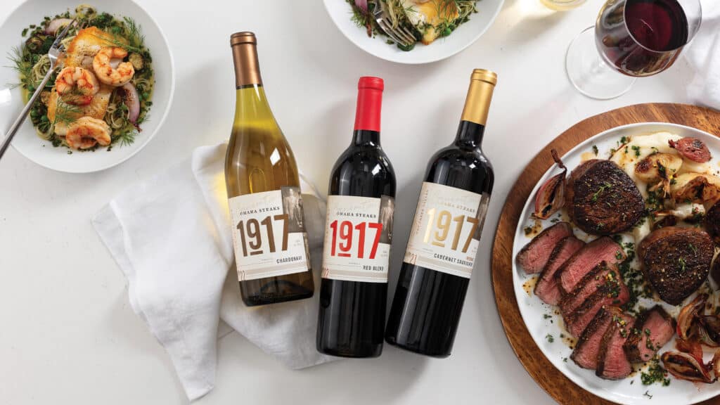 three bottles of wine and plate of filet mignon on table