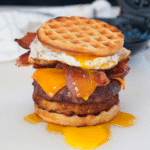 Brunch burger with an all-beef patty, rustic hashbrown, cheese, crispy bacon, fried egg, maple syrup and sandwiched between two toasty waffles.