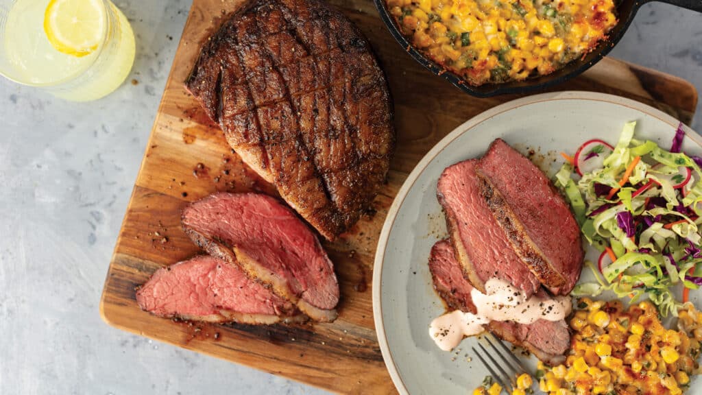Grilled Sirloin Cap Roast With Harissa Crema, Mexican Creamed Corn, and Vinegar Slaw