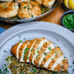 Pan-seared chicken breast sliced with pan sauce on a grey plate