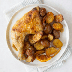 White plate with roasted potatoes and lemon chicken leg quarter