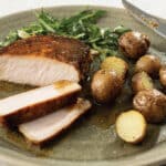 Mustard-Glazed Pork Chops with Steakhouse Potatoes and salad on a light green plate.